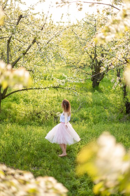 Young attractive girl walks in spring green park enjoying flowering nature