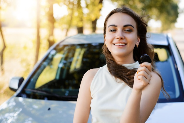 Young attractive girl wearing white Tshirt standing in front of the new car