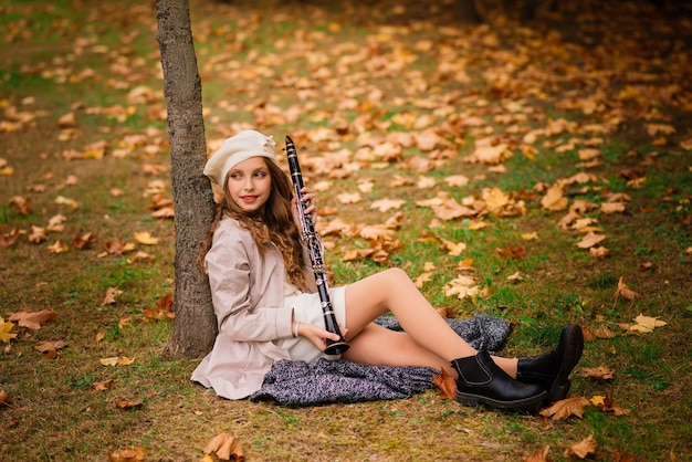 Young attractive girl with clarinet, ebony in fall park