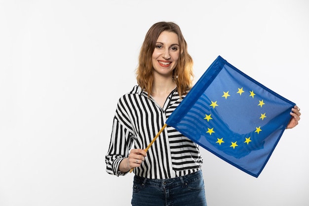 Foto giovane ragazza attraente con la bandiera dell'unione europea uno studente tiene la bandiera della unione europea in