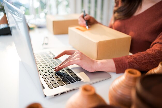 Photo a young attractive girl writes the address of the customer on the parcel to send