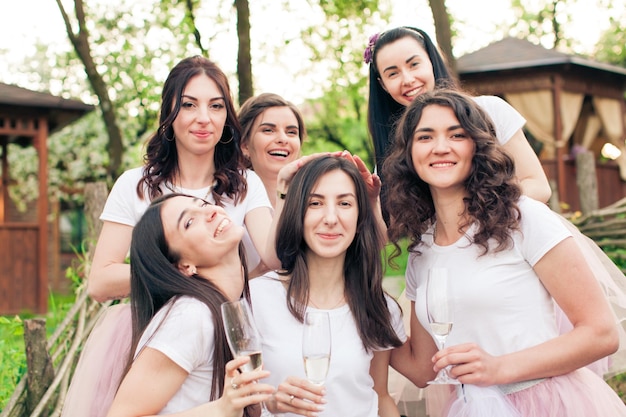 Young attractive girlfriends carring head of their friend, bride to be. Adorabale women having fun at spring outdoor party, posing, looking at the camera