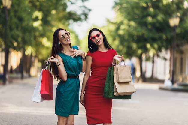 夏の街で買い物袋を持つ若い魅力的な女の子。