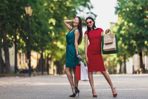 夏の街で買い物袋を持つ若い魅力的な女の子。