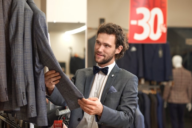 Young attractive groom in grey costume holding jacket.