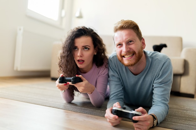 Young attractive happy couple playing video games at home