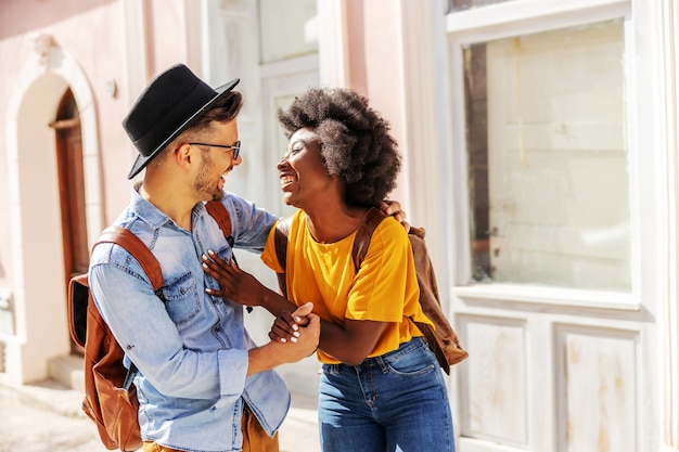 Young attractive happy multiracial couple standing outdoors on a beautiful sunny day flirting.