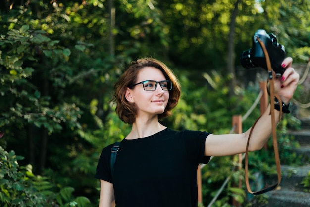 젊은 매력적인 hipster 여자 여자 야외에서 레트로 카메라로 selfie 초상화를 걸립니다