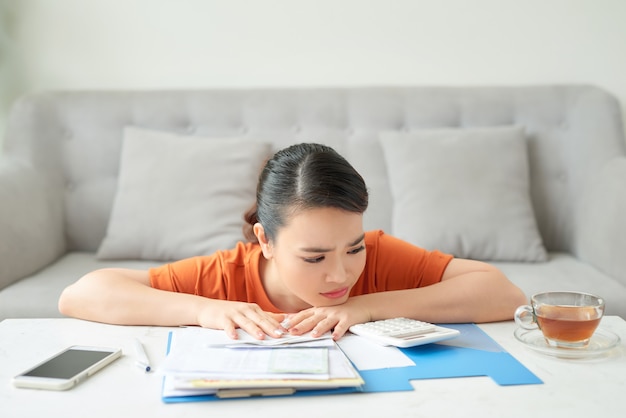 Young attractive housewife upset by utility bills, she counts family budget and pays bills online, being at home