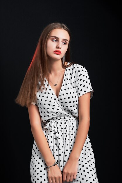 Young attractive long-haired girl posing in studio against black.