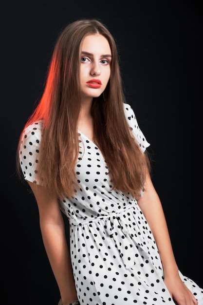 Young attractive long-haired girl posing in studio against black.