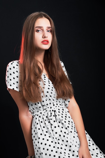 Young attractive long-haired girl posing in studio against black.