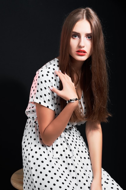 Young attractive long-haired girl posing in studio against black.