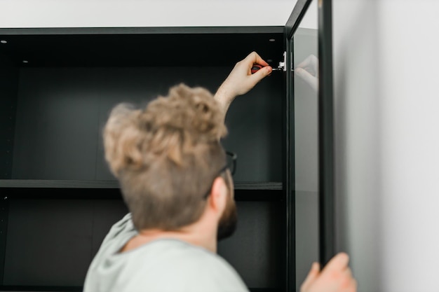 Photo young attractive man assembles furniture handwerker and interior objects concept