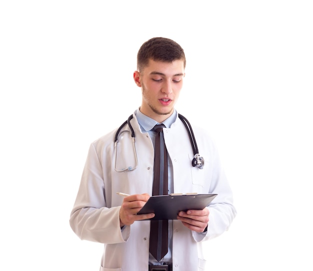 Young attractive man in blue shirt tie and doctor gown with stethoscope on his neck holding folder