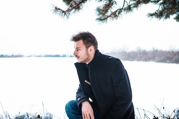 Young attractive man embracing the snow in winter. Closeup Portrait