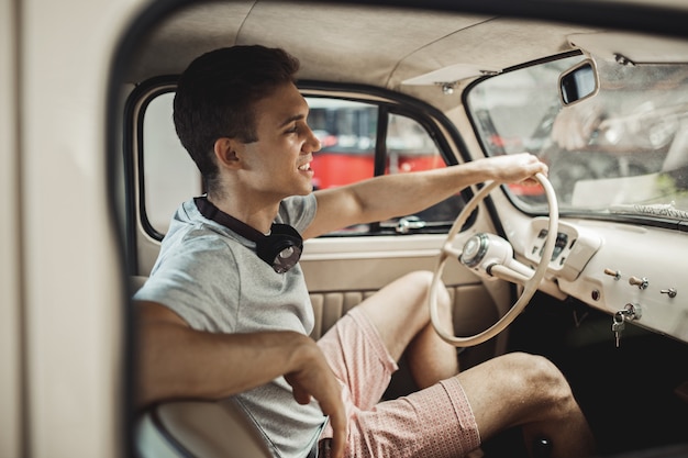 A young and attractive man is driving a vintage car.