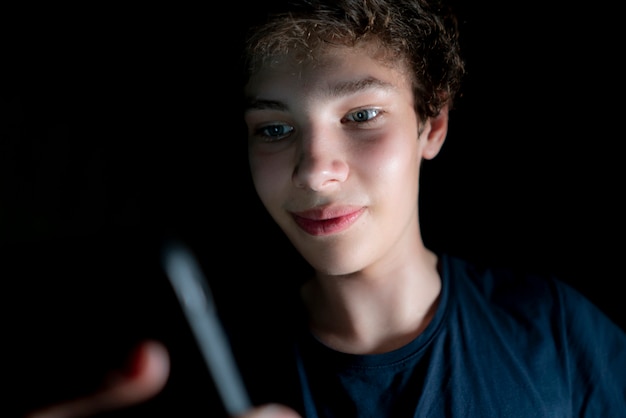 Молодой привлекательный мужчина использовать мобильный телефон поздно ночью в темной комнате