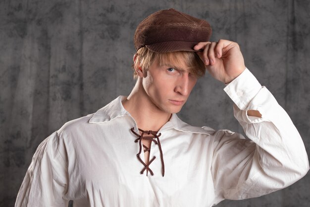 A young attractive man in a vintage retro outfit a brown leather cap