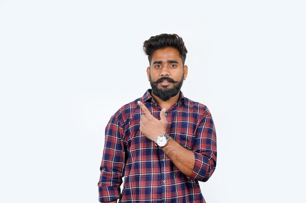 Young attractive man with a broad smile on his face and casual clothing pointing to the side while facing the camera