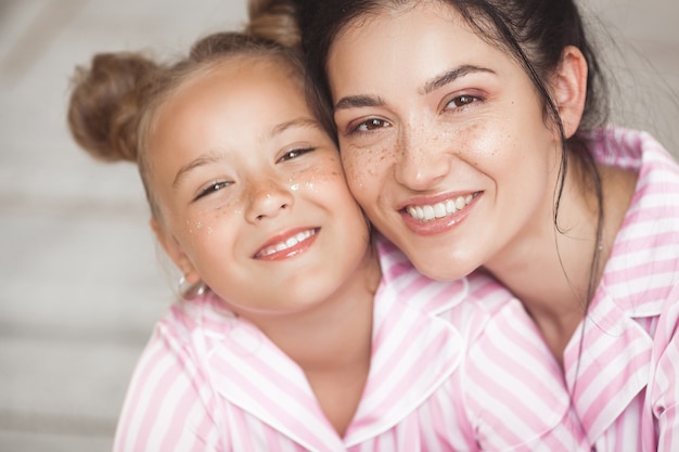 写真 若い魅力的な母親とパジャマパーティーで楽しんでいる彼女の小さな娘。朝の家族