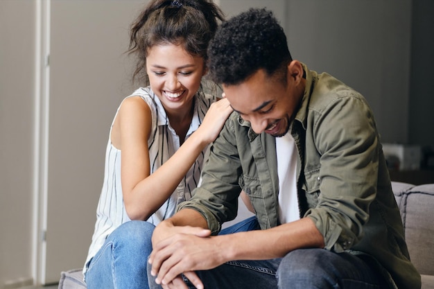 Young attractive multinational casual couple happily laughing together at cozy home