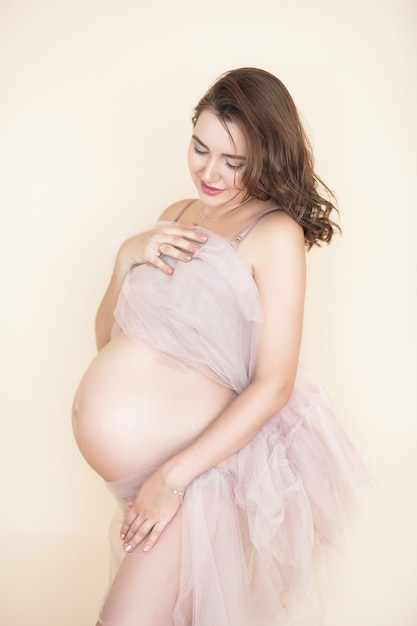 Молодая привлекательная беременная женщина в помещении. Концепция материнства.
