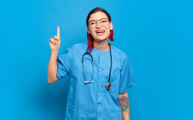 Young attractive red hair woman feeling like a happy and excited genius after realizing an idea, cheerfully raising finger, eureka!. hospital nurse concept