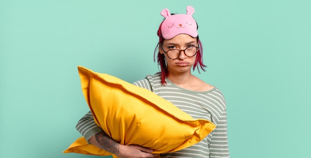 Young attractive red hair woman feeling sad and whiney with an unhappy look, crying with a negative and frustrated attitude and wearing pajamas.