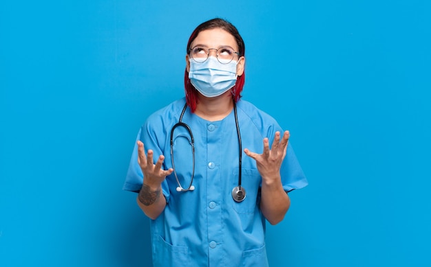 Young attractive red hair woman looking desperate and frustrated, stressed, unhappy and annoyed, shouting and screaming. hospital nurse concept