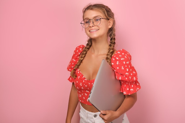Photo young attractive smiling caucasian woman teen with laptop stands in studio