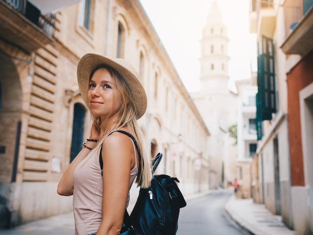 Young attractive smiling girl tourist exploring new city at summer