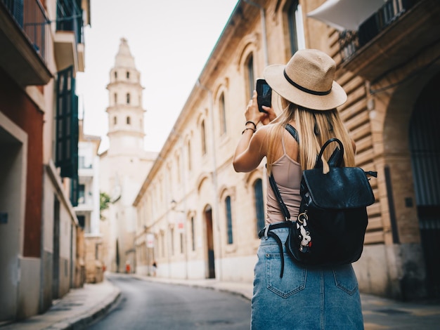 Young attractive smiling girl tourist exploring new city at summer