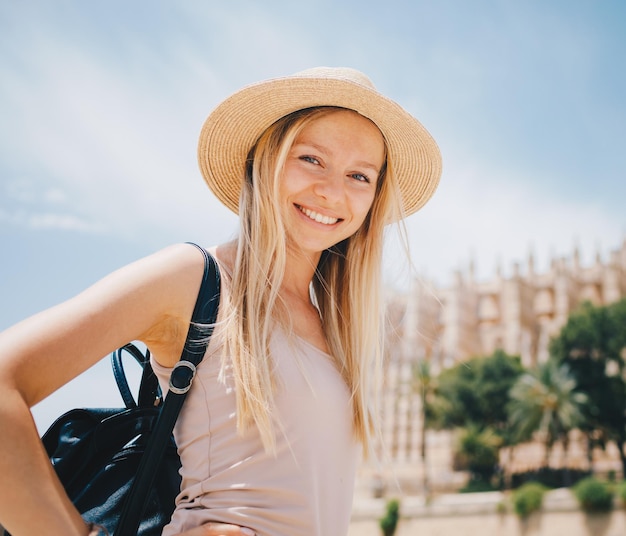 Young attractive smiling girl tourist in hat exploring new Europe city at summer holiday