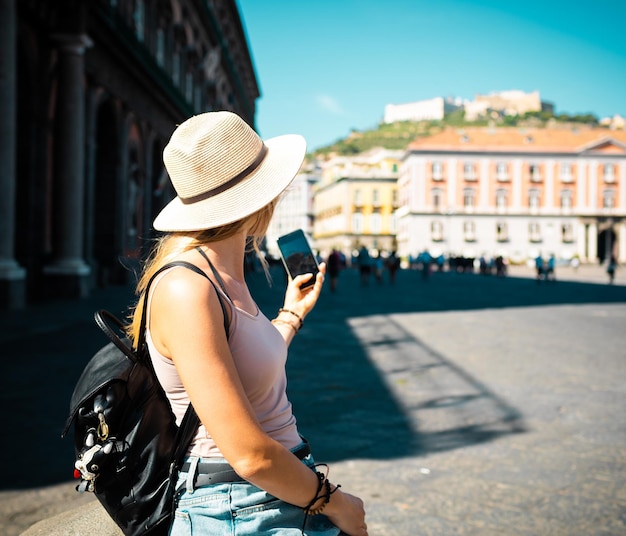 Young attractive smiling girl tourist in hat exploring new Europe city at summer holiday