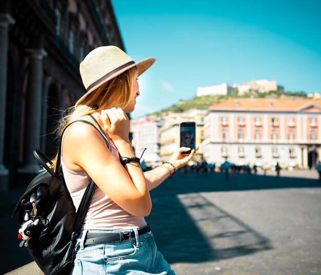 Young attractive smiling girl tourist in hat exploring new Europe city at summer holiday