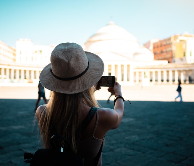 写真 夏休みに新しいヨーロッパの街を探索する帽子をかぶった若い魅力的な笑顔の女の子の観光客