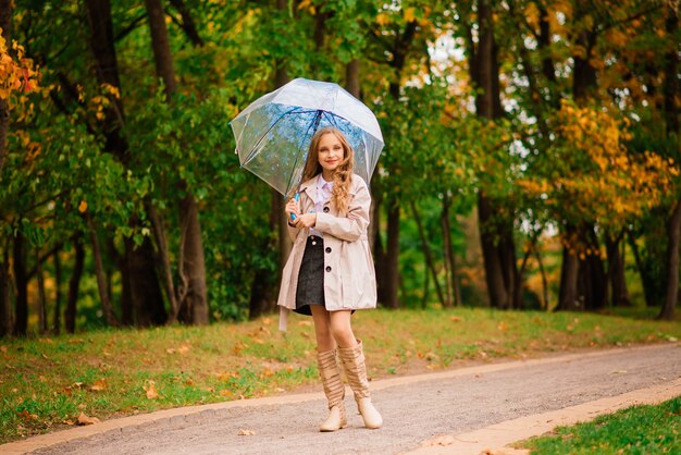 Young attractive smiling girl under umbrella in an autumn forest