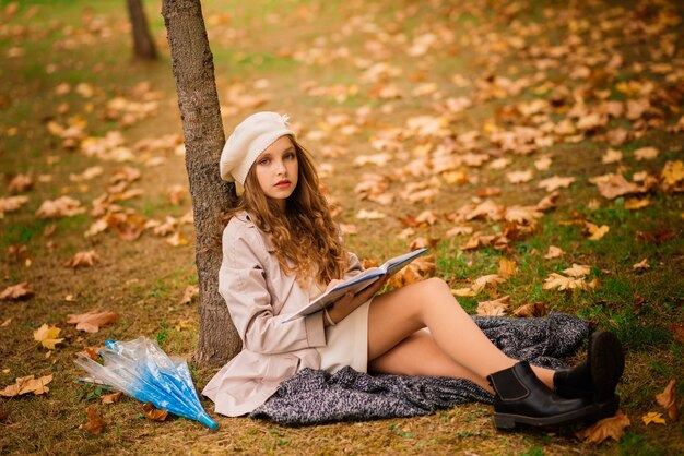 Young attractive smiling girl under umbrella in an autumn forest