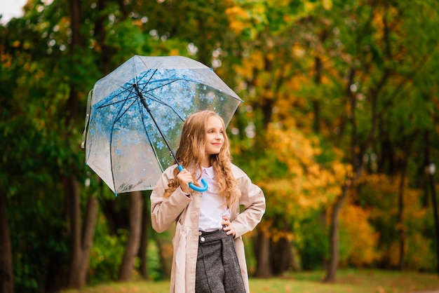 Young attractive smiling girl under umbrella in an autumn forest