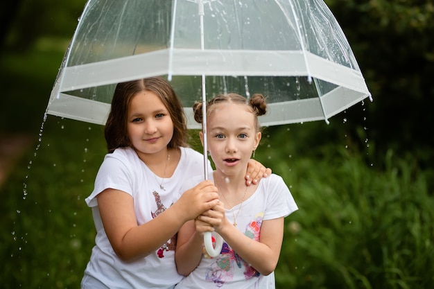 여름 공원에서 우산 아래 젊은 매력적인 웃는 소녀 소녀 놀란 얼굴