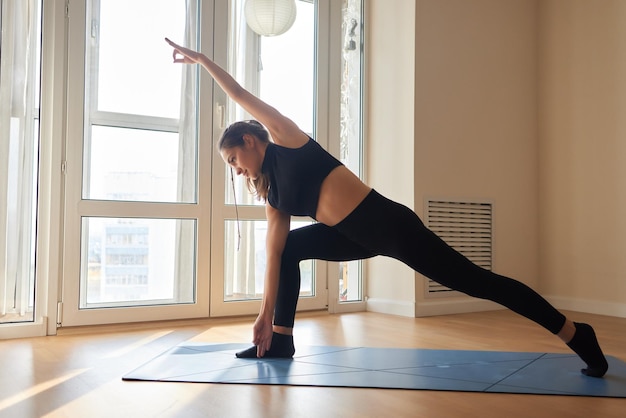 Young attractive smiling woman practicing yoga wearing sportswear pants and top indoor full length a
