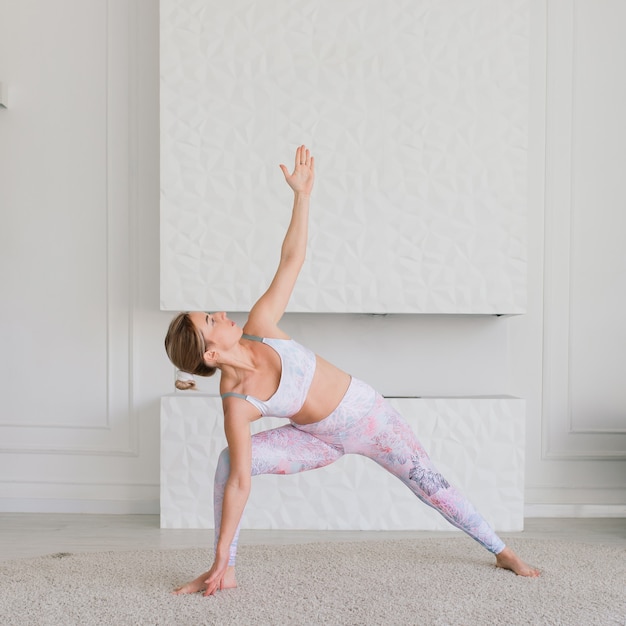 Young attractive smiling woman practicing yoga, working out, wearing sportswear, bra, home training