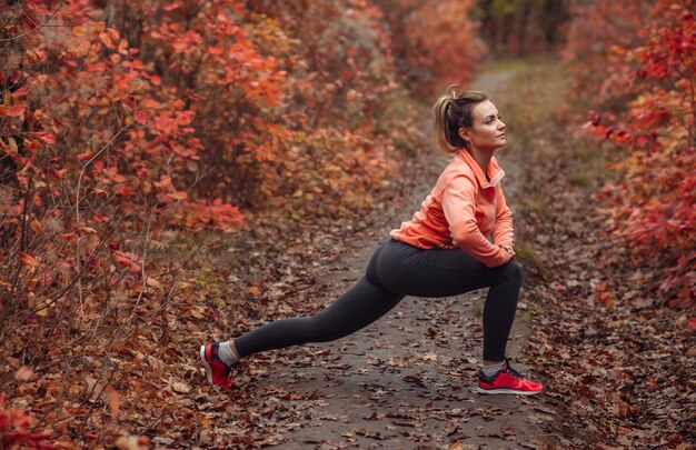 Молодая привлекательная спортивная женщина в спортивной одежде делает упражнения на растяжку ног
