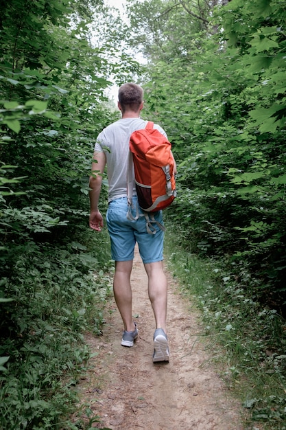 Young attractive sporty man walking along a path in the forest