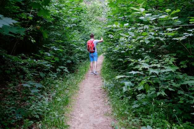 Foto giovane uomo sportivo attraente che cammina lungo un sentiero nella foresta