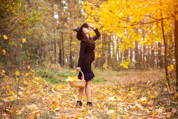 写真 若い魅力的な魔女が秋のオレンジ色の森を歩くhelloweenコンセプト