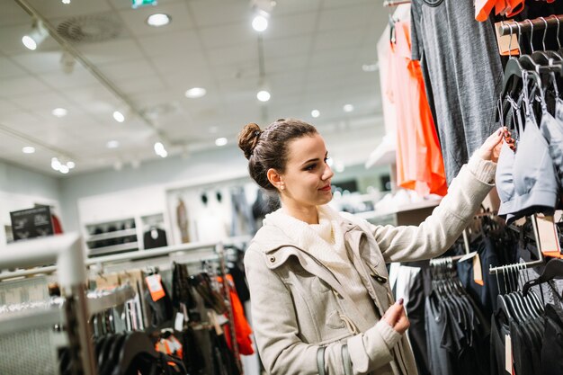 Молодая привлекательная женщина покупает одежду в торговом центре
