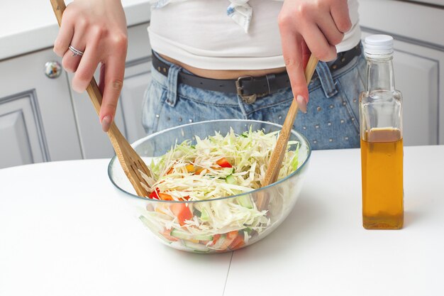 Young attractive woman cooking salad indoors at the kitchen