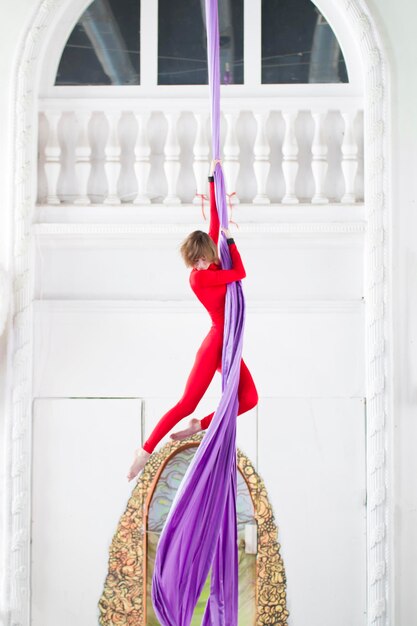 Молодая привлекательная женщина делает гимнастические элементы на воздушном шелке